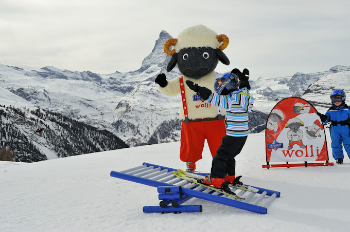 Wolli Park Sunnegga in Switzerland - a group of people standing on top of a snow covered mountain.