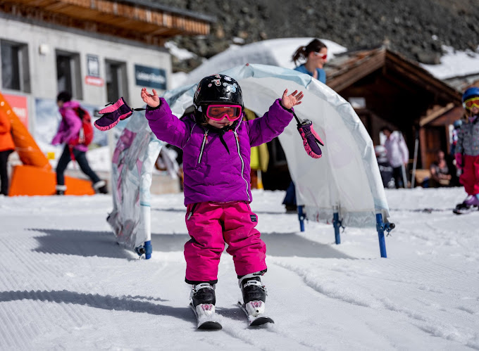 Wolli Park Sunnegga in Switzerland - a little girl in a purple jacket on a snowboard.