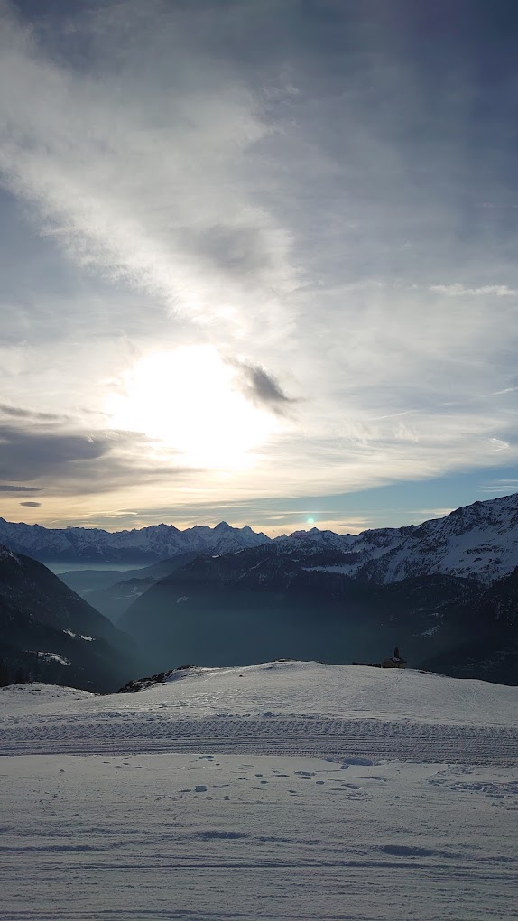 Cime Bianche Funivie Valtournenche in Italy - the sun is shining through the clouds over the mountains.