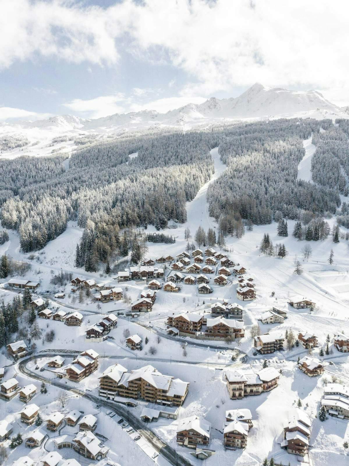 Skiing scene at the Ski-Waldheimat Hauereck resort in Styria, Austria, featuring bustling winter sports activities amidst stunning wintry landscape, with a chalet in the backdrop.