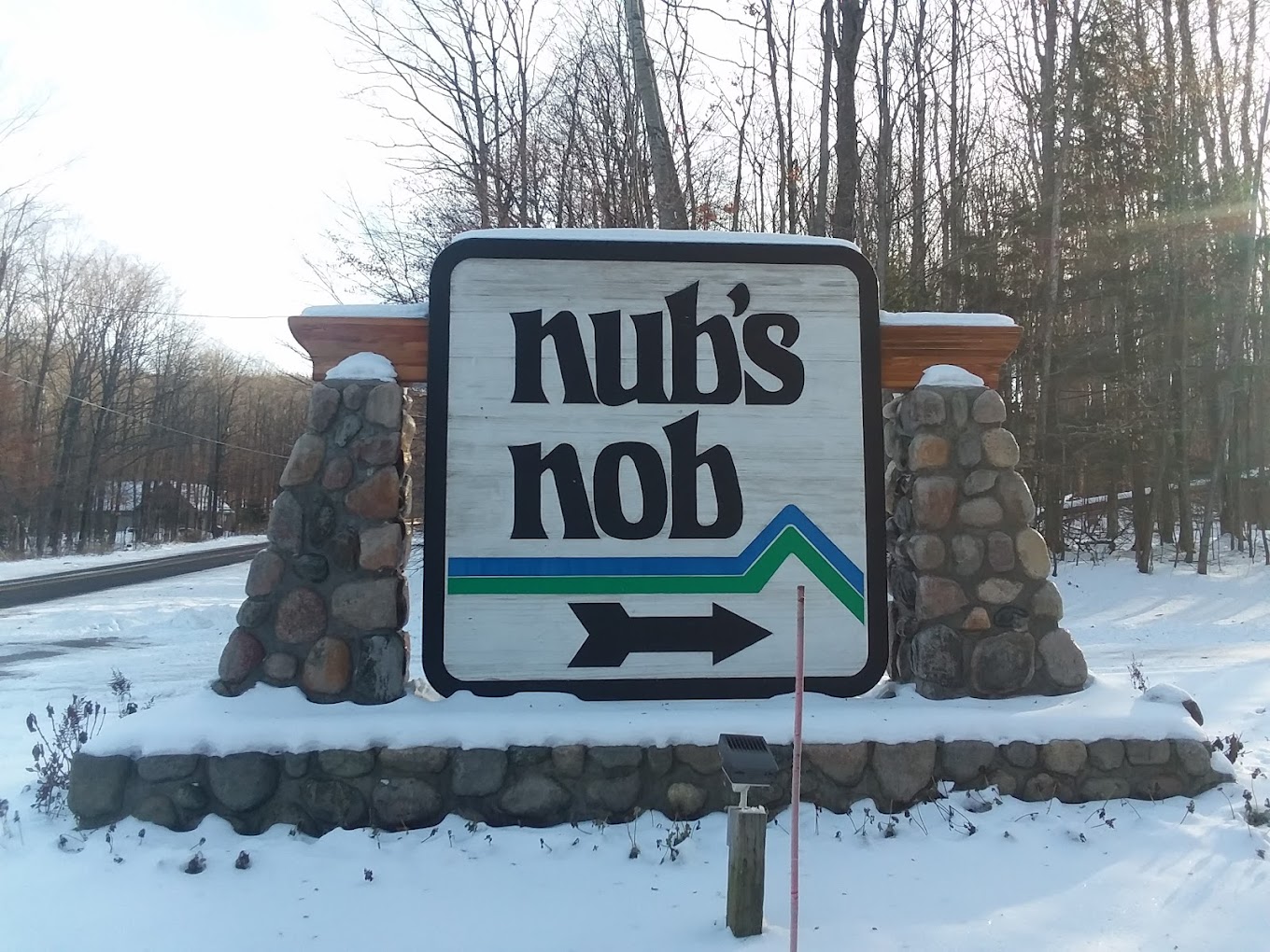 Nubs Nob Ski Area in USA - a sign that is in the snow near some trees.