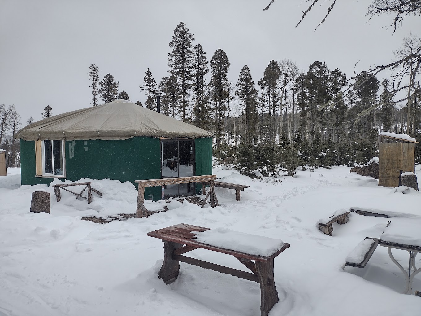 Enchanted Forest Cross Country Ski Area in USA - a tent sits in the snow next to a picnic table.