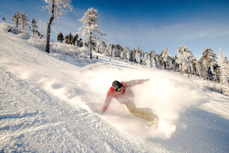 A dynamic winter sports scene at Bear Mountain – Big Bear Lake in California highlighting the presence of a skier and a snowboarder in action with a distant view of a snowmobile and the ski resort.