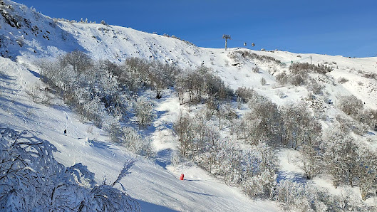 View of Bear Mountain, Big Bear Lake, California, featuring a lively ski resort complete with skiers enjoying winter sports, ski lifts in operation amidst stunning winter scenery.