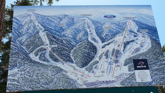 A winter scene at Bear Mountain – Big Bear Lake ski resort in California featuring a ski lift skiers and snow-covered slopes.