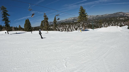 A skier enjoys a snowy slope at the Bear Mountain – Big Bear Lake a popular ski resort in California. Nearby a ski lift can be seen suggesting an active winter sports scene.