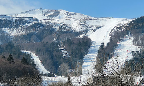 View of Super-Besse ski resort in France showing snow-covered slopes, a charming challet, and a bustling winter sports scene at the centre.