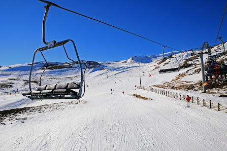 A scenic view of Super-Besse ski resort in France featuring a ski lift bustling winter sports activity a quaint chalet and snow-covered slopes.
