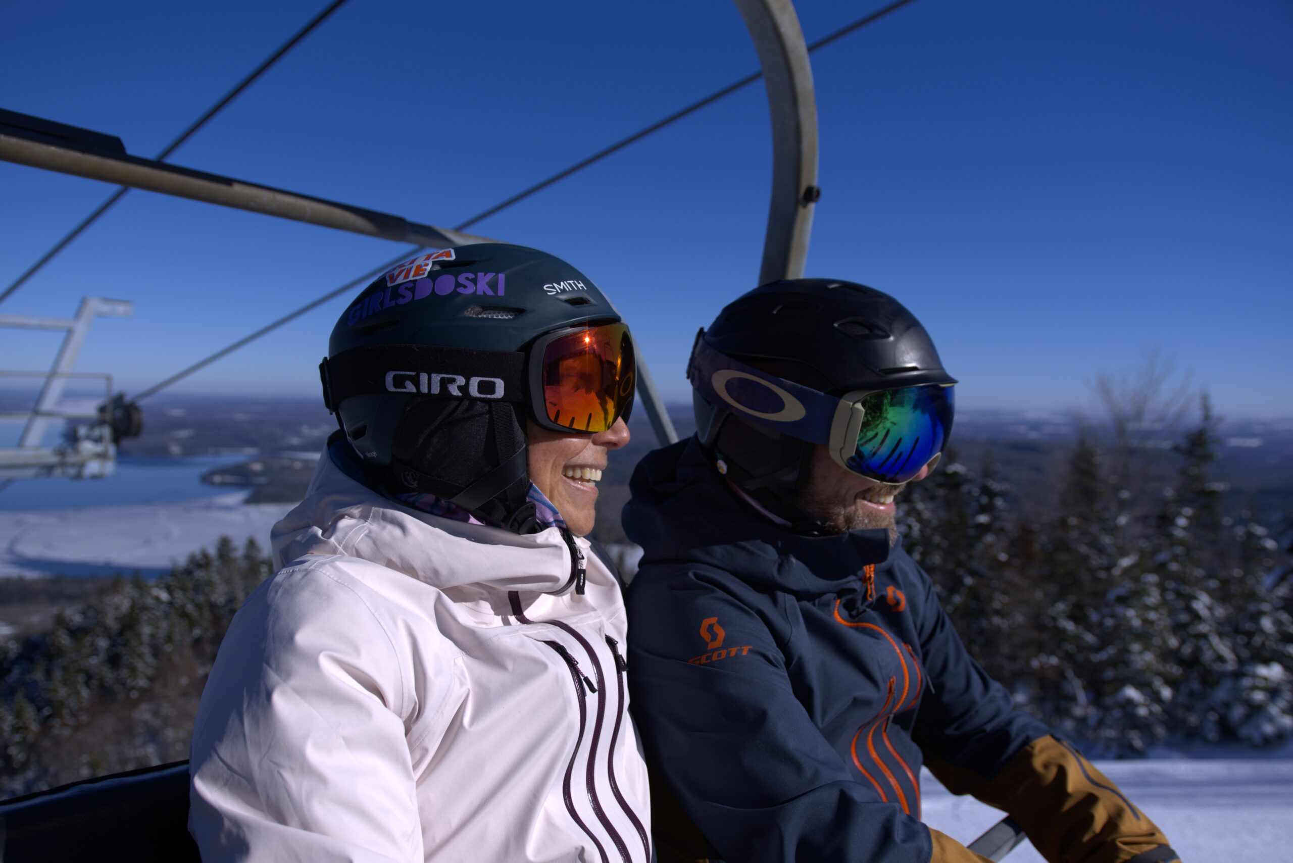 A skier descending the scenic slopes of Owl's Head in Quebec Canada. A ski lift operating in the background of the winter sports scene in a ski resort. A charming chalet is also visible.