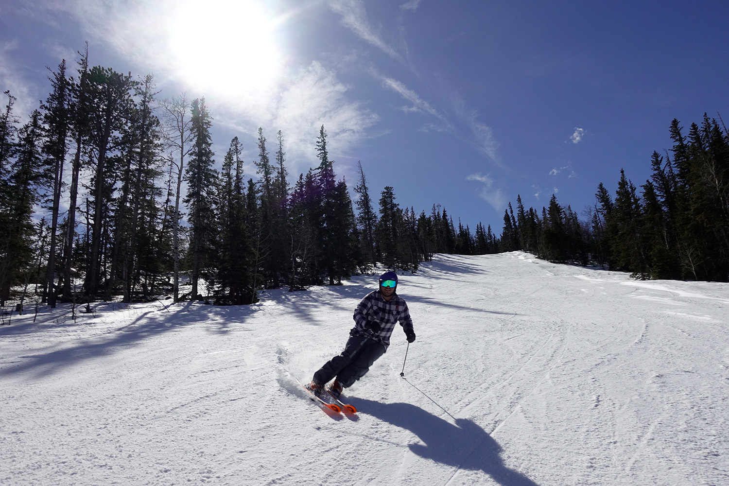 A winter sports scene at Terry Peak South Dakota USA featuring a skier and a snowboarder enjoying their rides down the snowy mountain near a ski resort and a ski lift.