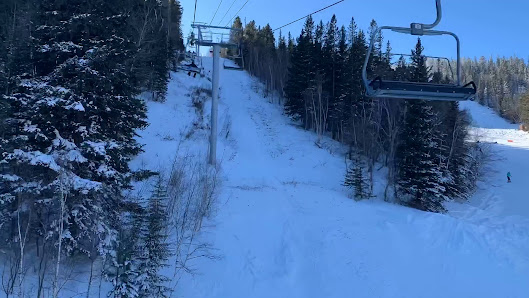 A skier glides down the snowy slopes at Terry Peak Ski Resort in South Dakota USA. In the background a ski lift ascends the mountain ready to bring more winter sports enthusiasts to the top.