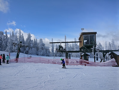 A picturesque view of Terry Peak's ski resort in Lead South Dakota showcasing a ski lift and skiers engrossed in winter sports amidst the snowy landscape.