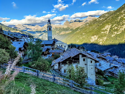 Scenic view of Antagnod Pian Pera featuring a charming chalet nestled into the picturesque landscape of the Monte Rosa ski resort in Italy. The winter scene is dominated by a towering, snow-capped mountain and a cozy mountain hut.