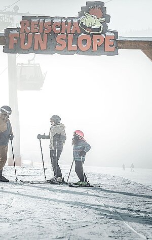 A family skiing together at the Hochficht ski resort in Mühlviertel Upper Austria surrounded by a beautiful winter landscape.