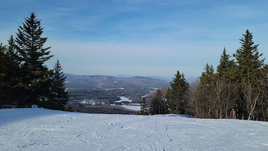A winter sports scene at Ragged Mountain ski resort in Danbury New Hampshire featuring a skier gliding down the snowy slope a ski lift in the background and a charming chalet nearby.