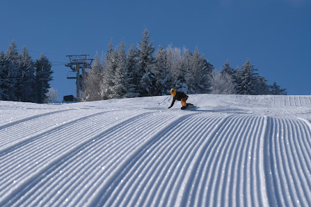 A skier skillfully navigating down Ragged Mountain in Danbury New Hampshire at a ski resort with a charming chalet and ski lift in the background perfectly encapsulating a winter sports scene.