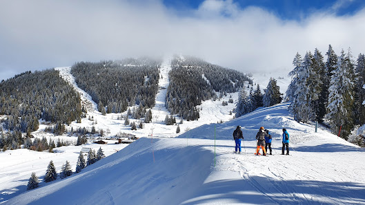 Winter scene at Collet ski resort in Allevard, France, featuring skiers enjoying the snow-covered slopes and a chalet nestled amidst the white landscape.