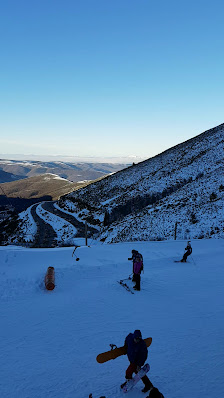 Winter sports scene at Valdezcaray in Ezcaray, La Rioja, Spain, with skiers navigating snow-covered slopes and a cosy chalet and winter sports centre nearby.