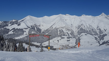 Image showcasing the snowy landscape of Valdezcaray ski resort in Ezcaray Spain featuring a challet in the background and skiers enjoying winter sports.