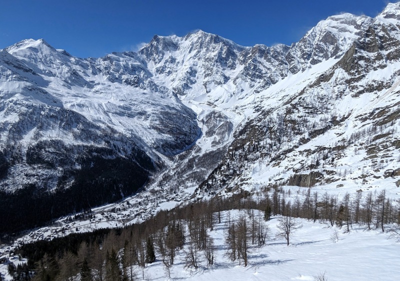 A picturesque scene in Macugnaga Italy featuring a charming chalet at a ski resort with a scenic mountain backdrop. A skier is seen enjoying the winter sports scene.