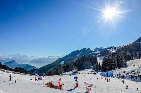 Winter sports enthusiasts enjoy a sunny day at the Station Brasses ski resort in Haute-Savoie, France, with a charming chalet nestled among the snowy landscape.