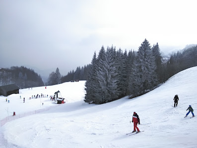 Winter scene at Station Brasses in Mont Blanc, France showcasing a bustling ski resort with a skier in action, set against the stunning backdrop of snow-clad slopes and crisp winter scenery.