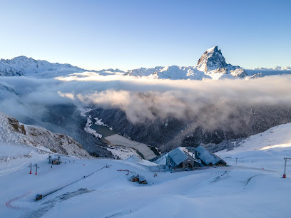Winter sports enthusiasts enjoying a day at Station Brasses in Mont Blanc, France, with a mountain hut nestled against the spectacular backdrop of snow-covered mountains.