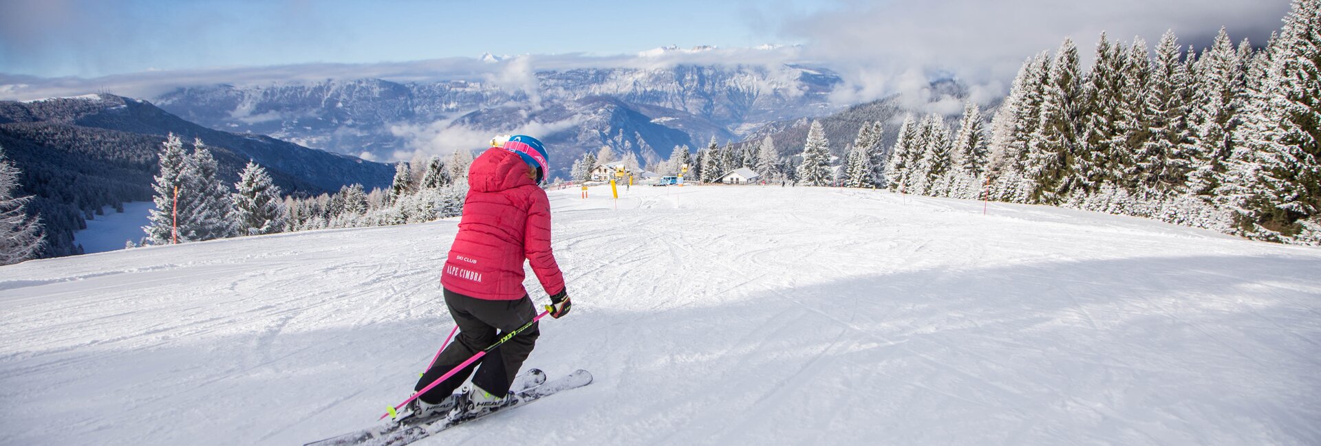 Alpe Cimbra | Folgaria in Italy - a woman in a pink jacket skiing down a mountain.