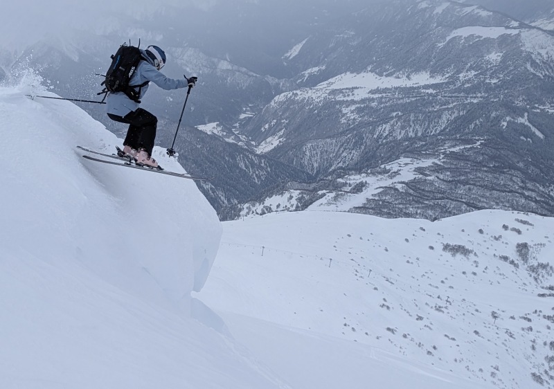 A skier and a snowboarder enjoying winter sports at the scenic Tetnuldi-Mestia ski resort in Samegrelo-Zemo Svaneti, Georgia, with a beautiful mountain backdrop.