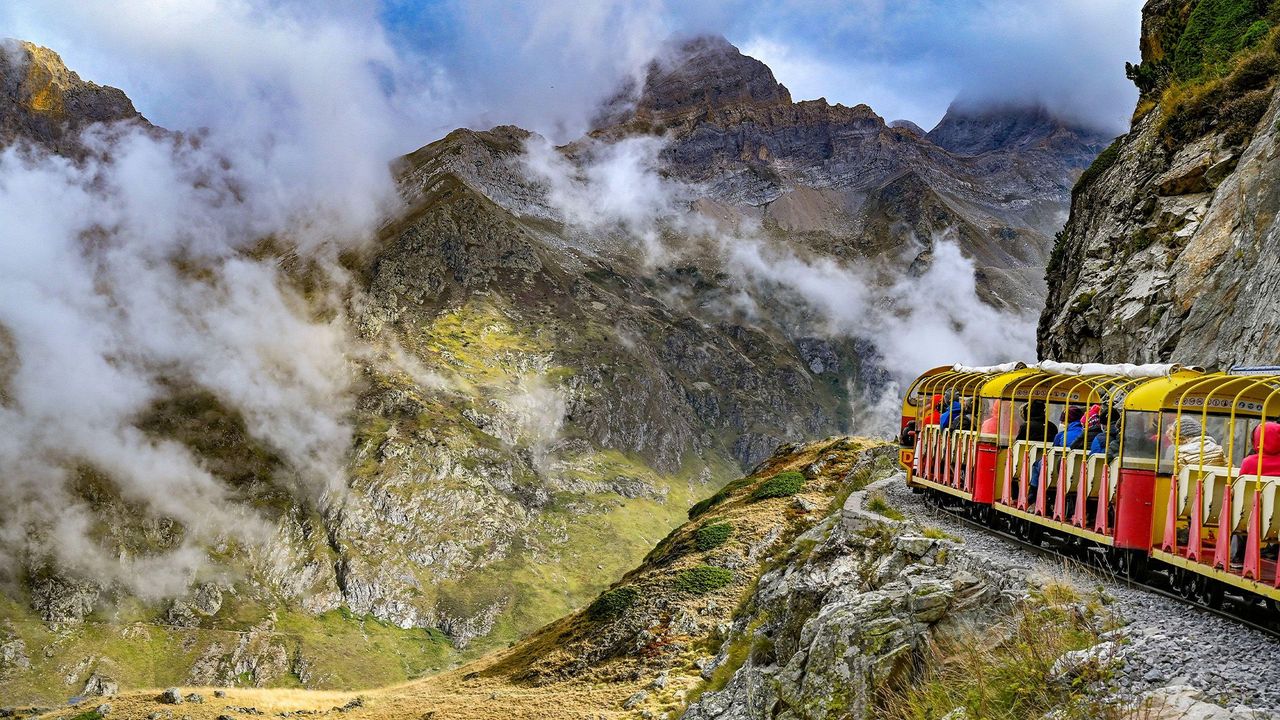 Petit train d'Artouste in France - a red and yellow train traveling through the mountains.