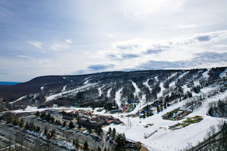 View of Camelback ski resort in Tannersville Pennsylvania featuring a winter sports scene with a ski lift snow-covered slopes and a challet in the background.