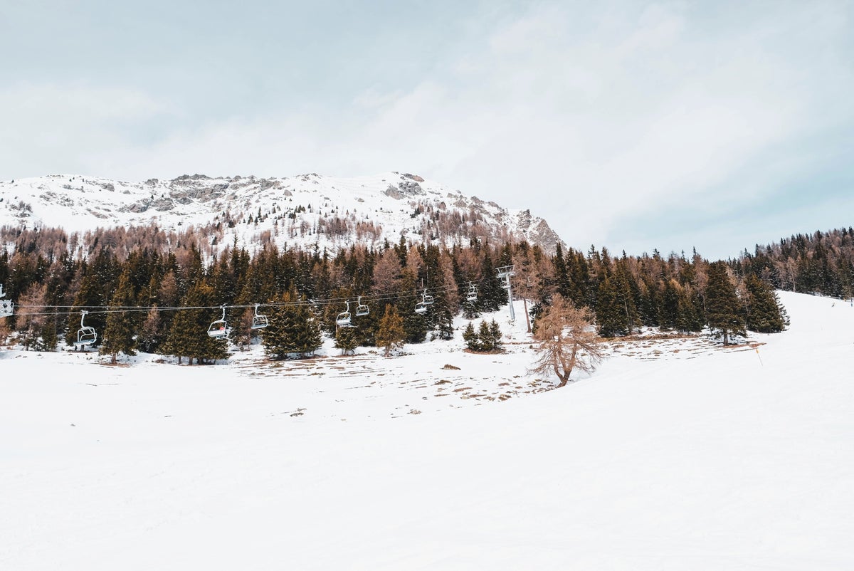 Impianti Risalita Torgnon Cervino in Italy - a snow covered mountain with trees in the fore.