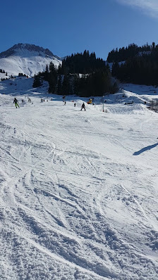 A picturesque ski resort in Torgnon Italy featuring a charming chalet alongside a bustling winter sports scene. A visible skier and ski lift add to the vibrant frosty atmosphere.