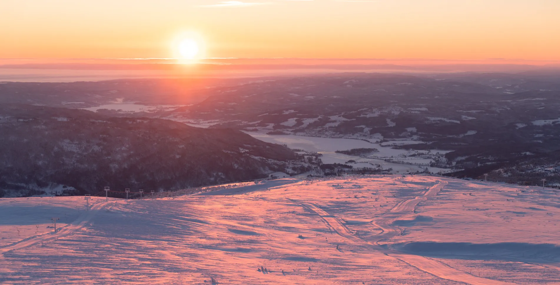 A skier enjoying a winter sports scene at Norefjell, Buskerud, Norway. The breathtaking landscape of the ski resort is set against a mountain under a clear sky.