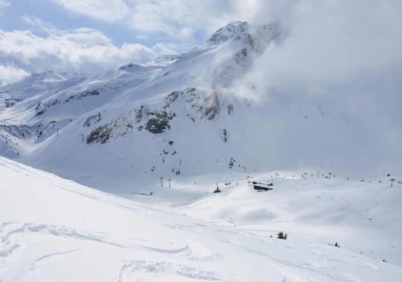 A skier gliding down the snow-covered slopes of Ski Arlberg resort in St Anton Austria surrounded by majestic mountains. A quintessential winter sports scene in Tyrol.