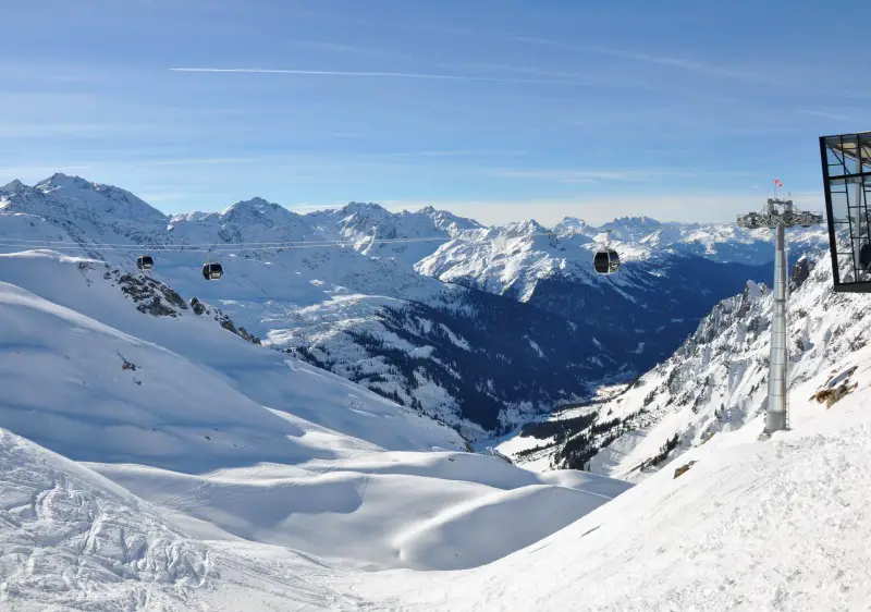 A picturesque view of Ski Arlberg St Anton in Tiroler Oberland Austria featuring a cozy challet nestled amongst snowy slopes bustling with winter sports enthusiasts in the heart of a well-appointed ski resort.