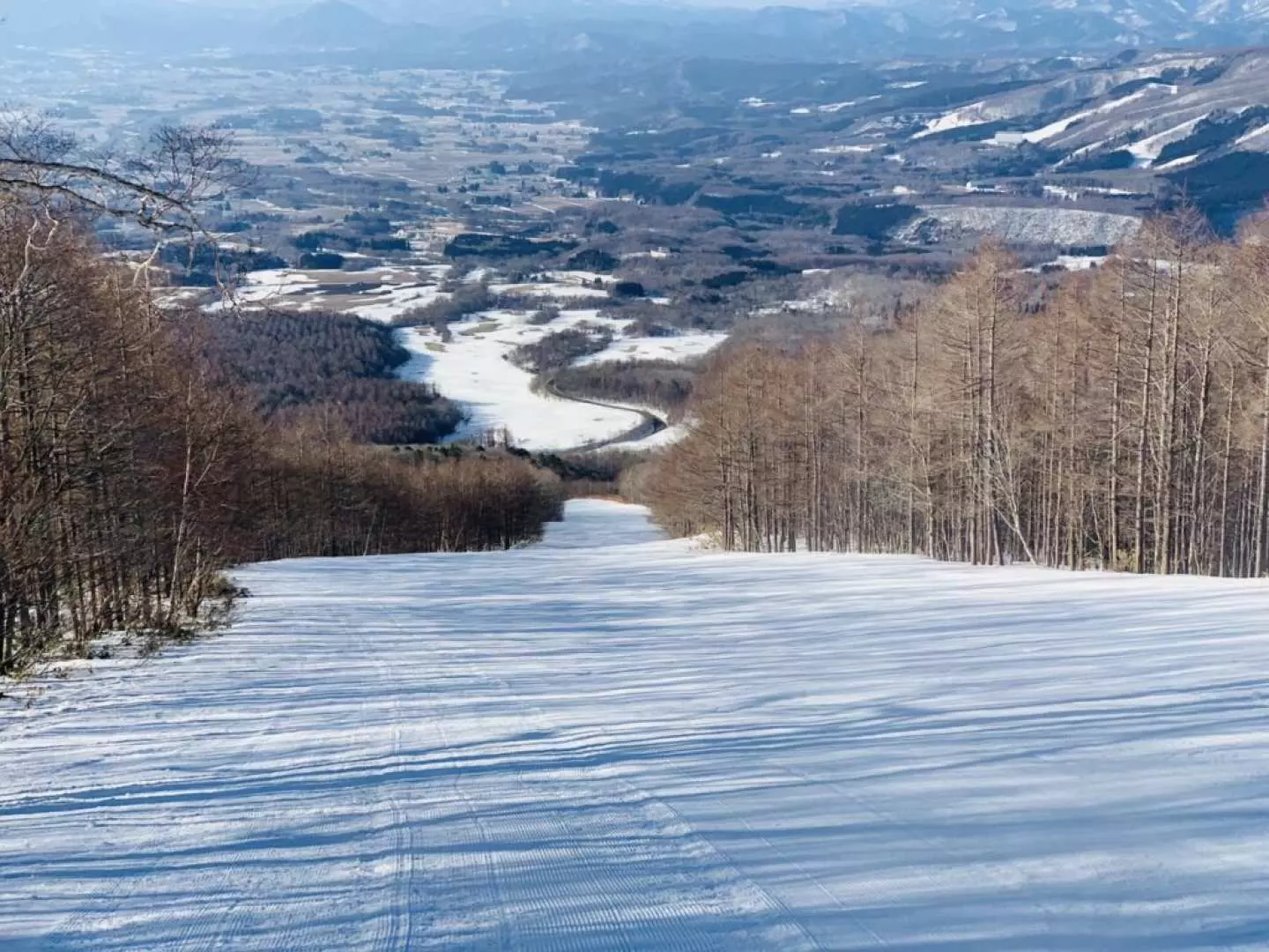 Iwate Kogen in Japan - a ski slope with trees and mountains in the background.