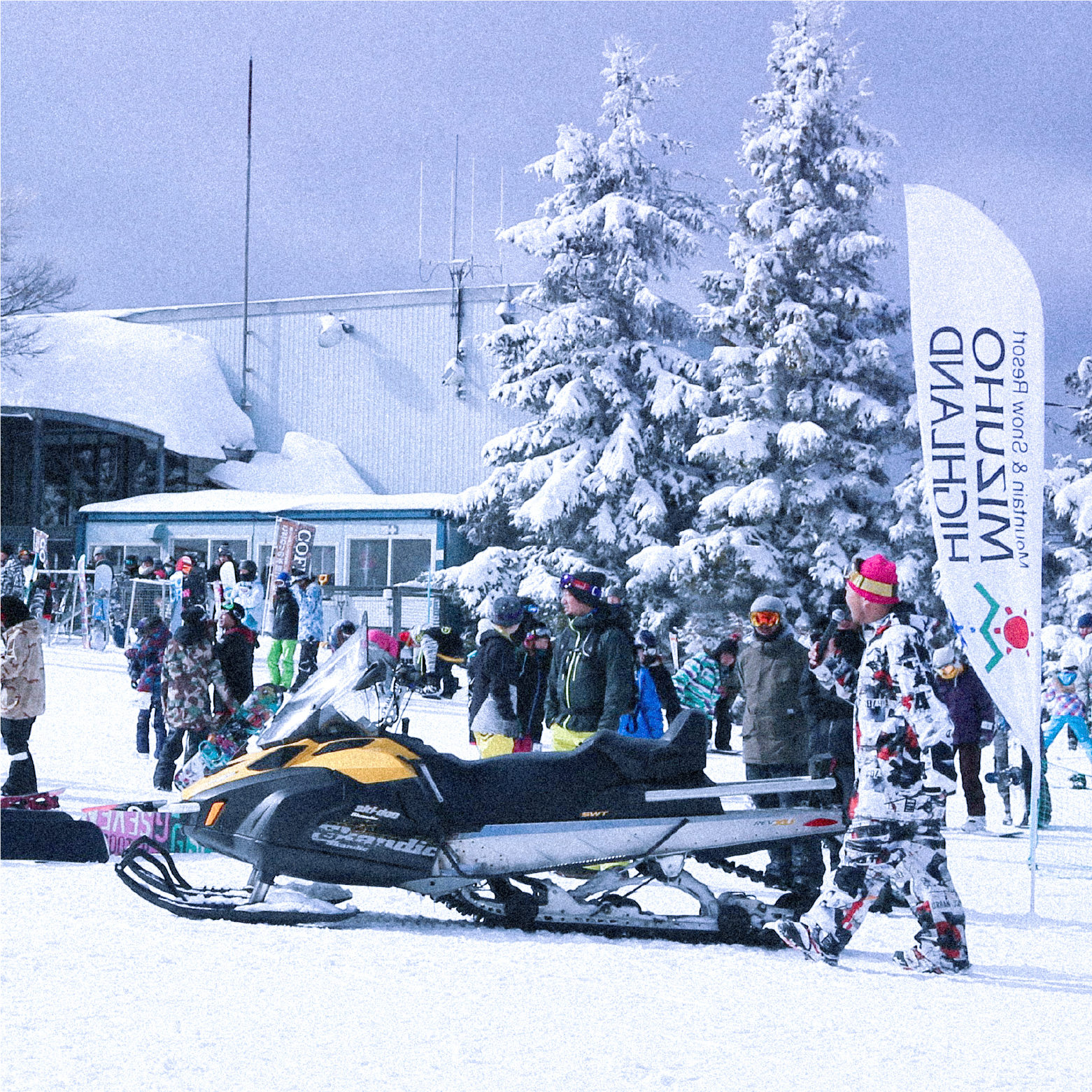 Skiing scene at Mizuho Highland, Shimane, Japan, featuring a snowmobile and various skiers enjoying the winter sports facilities amidst the snow-covered landscape.