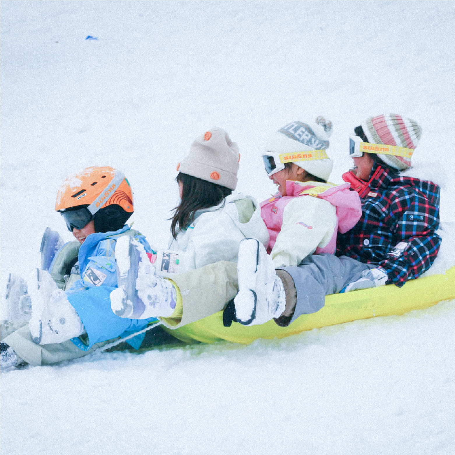 A family enjoying a day of winter sports at the Mizuho Highland ski resort in Japan, complete with a snowmobile nearby and a chalet in the backdrop.
