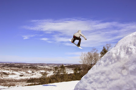 A snowboarder skillfully skims down the snowy slopes of Blue Mountain in Palmerton Pennsylvania leaving a flurry of powder in their wake.