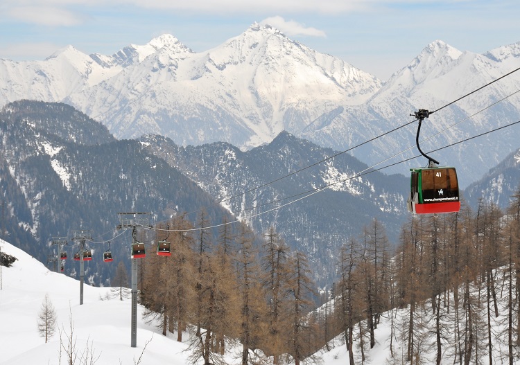 A stunning winter scene from Champorcher in Aosta, Italy featuring a ski lift amidst the ski resort with a skier enjoying the winter sports scene.