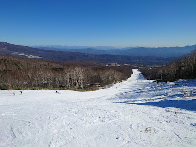 A vibrant scene at Palcall Tsumagoi ski resort in Japan, featuring a lively winter sports activities with skiers ascending the mountain via ski lift amidst beautiful winter scenery.