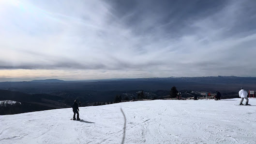 Winter sports enthusiasts enjoying a day on the slopes at a ski resort in Santa Fé, New Mexico. A skier can be spotted mid-action against the stunning backdrop of the mountains.