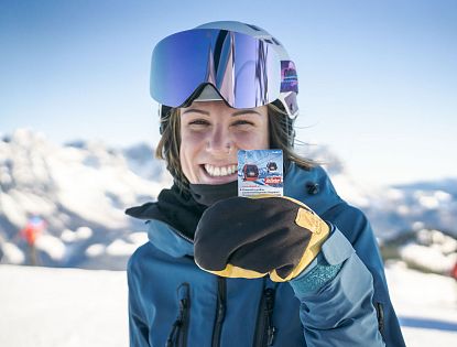 A skier and a snowboarder enjoying a winter sports scene at SkiWelt Brixental resort in Tyrol, Austria with a charming challet in the background.