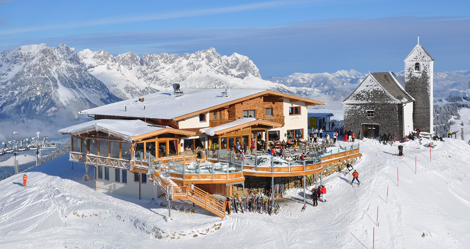 SkiWelt Brixental resort in Austria featuring a winter sports scene with bustling skiers and snowboarders, a cozy chalet under a blanket of snow, and beautiful panoramas of snow-swept mountains.