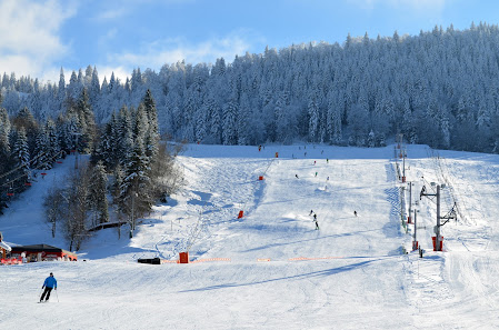 Winter scene in Métabief, France, with a bustling ski resort, a sports centre, a quaint challet nestled among the snow-covered slopes, all awash in the beauty of winter scenery.