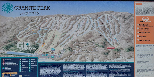 View of Granite Peak at Rib Mountain State Park in Wausau, Wisconsin, featuring a bustling ski resort. The landscape is decorated with snow-covered slopes and a mountainous backdrop.