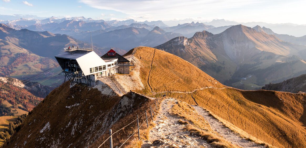 View of Moléson mountain in Switzerland, showcasing a cozy mountain hut, a bustling winter sports centre, and a nearby ski resort, all immersed in stunning winter scenery.
