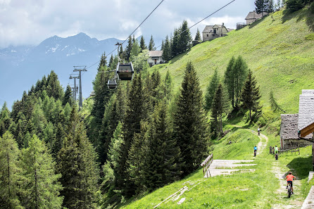 Ski lift and resort in Piana di Vigezzo – Craveggia | Santa Maria Maggiore in Prestinone, Italy, with a quaint chalet nearby. The backdrop features a towering mountain.