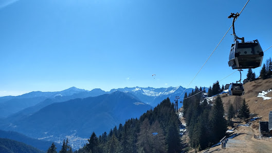 A scenic view of Piana di Vigezzo in Italy. A charming chalet sits amidst the snowy landscape with a ski lift nearby. Skiers can be seen enjoying the winter sports the ski resort offers.